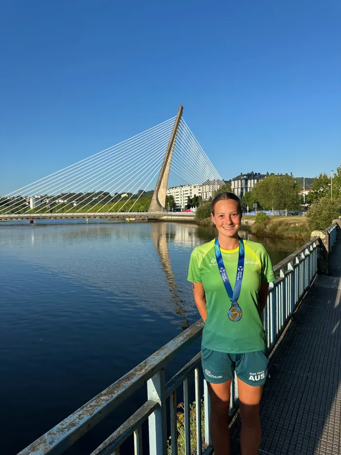 A swimmer wearing her medal on a riverside bridge at an away meet