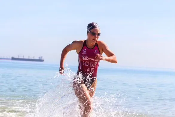 A triathlete running out of the surf in a race suit